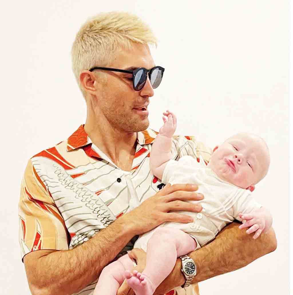 Jacob Jules Villere holding his baby in a scenic outdoor setting.